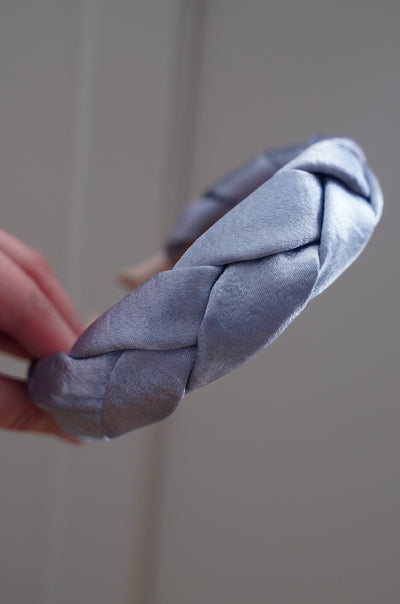 Hand holding a knotted gray fabric against a plain background