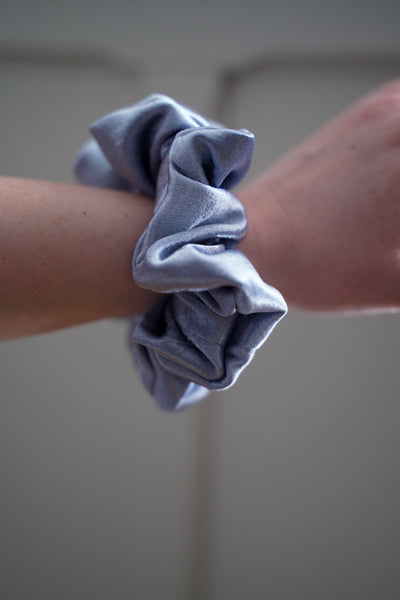 Light blue scrunchie on a wrist against a neutral background